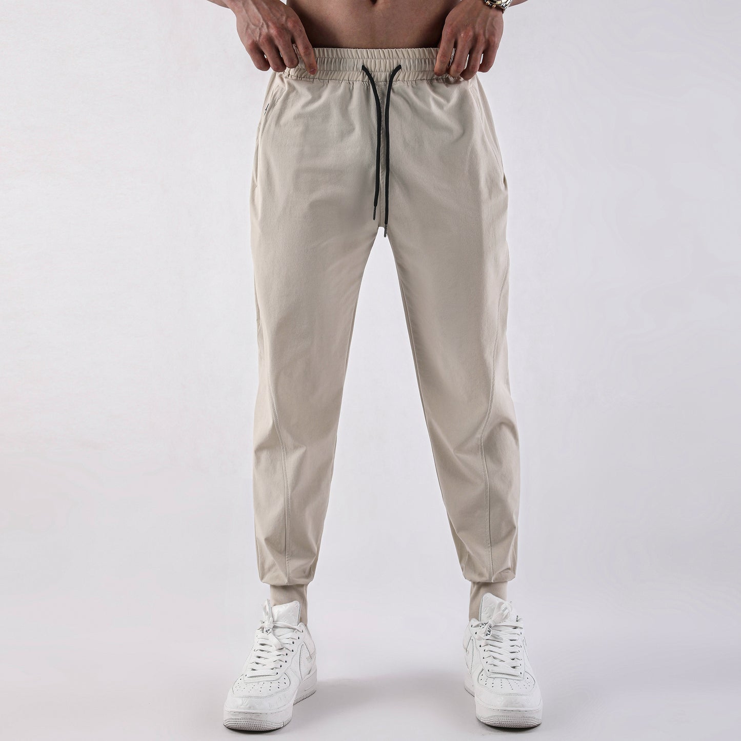 Beige jogger pants worn by a person on a white background