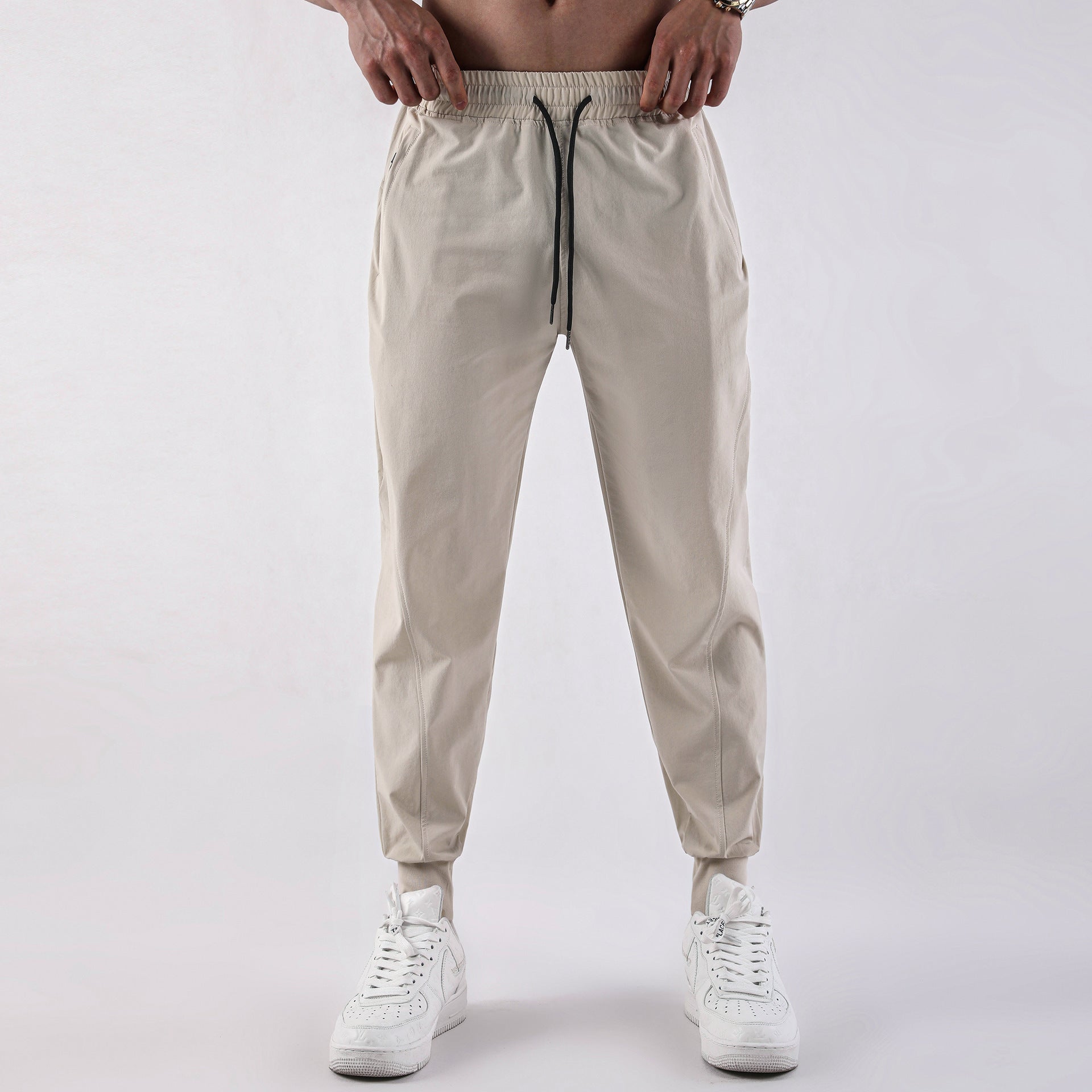 Beige jogger pants worn by a person on a white background