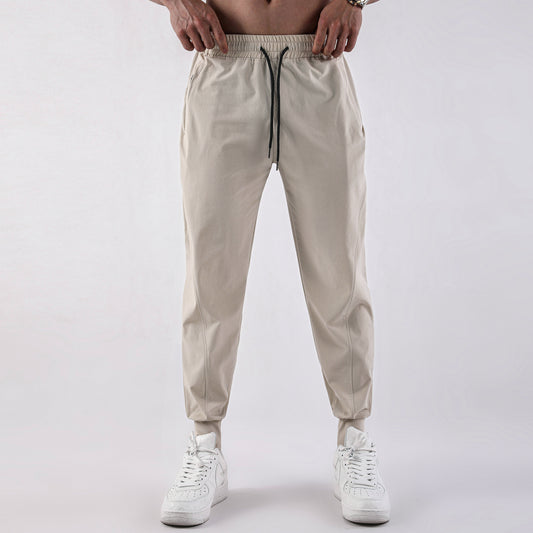 Beige jogger pants worn by a person on a white background
